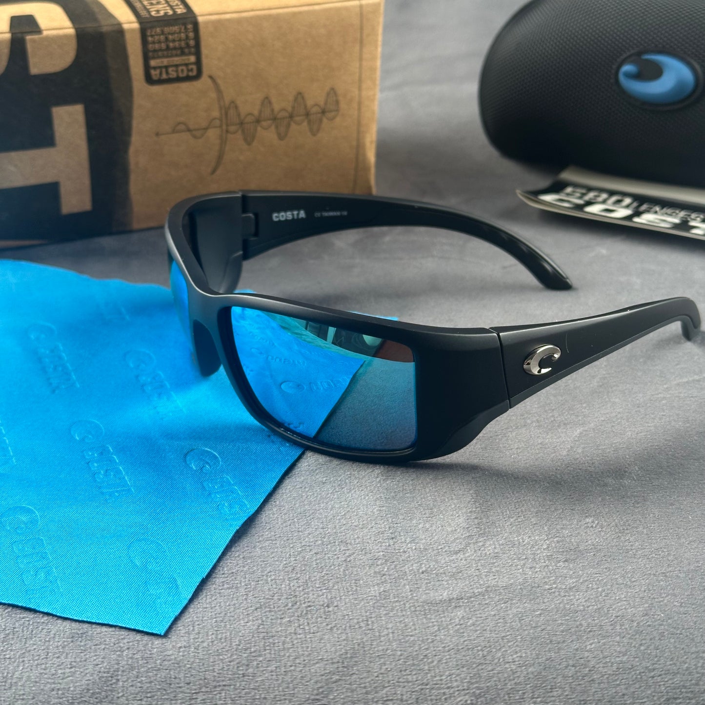 Matte black frame sport sunglasses with blue mirror lenses, including a protective case and cloth.