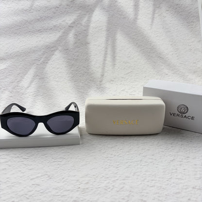 Black cat-eye sunglasses featuring gold-toned baroque temple embellishments on a white textured base