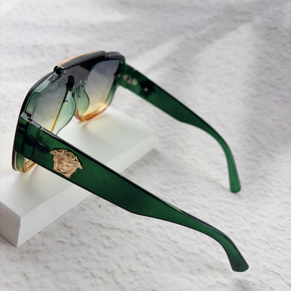 Oversized geometric sunglasses with green-to-yellow gradient lenses and gold metallic frame details.