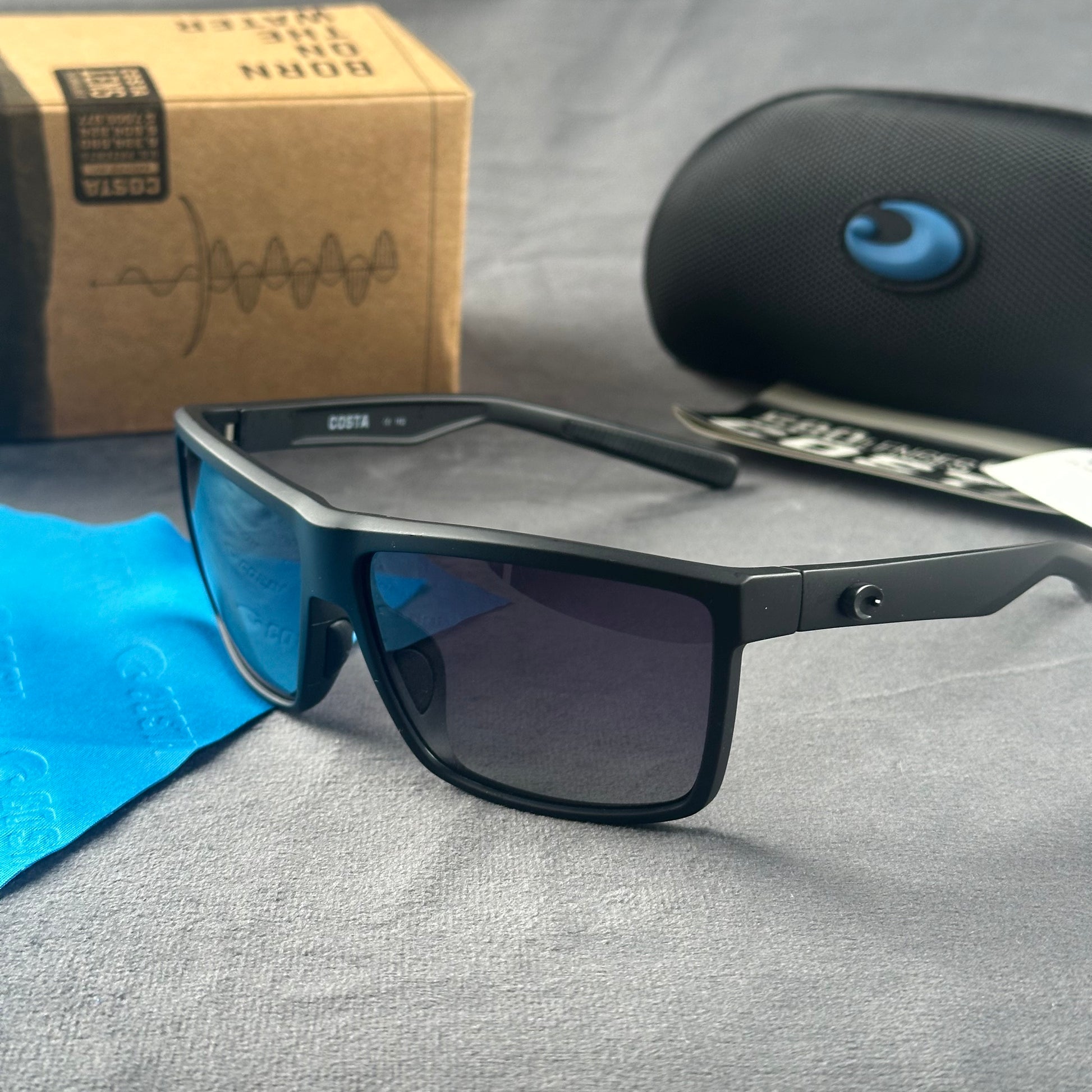Matte black sport sunglasses with polarized blue-tinted lenses, hard case, and cleaning cloth.