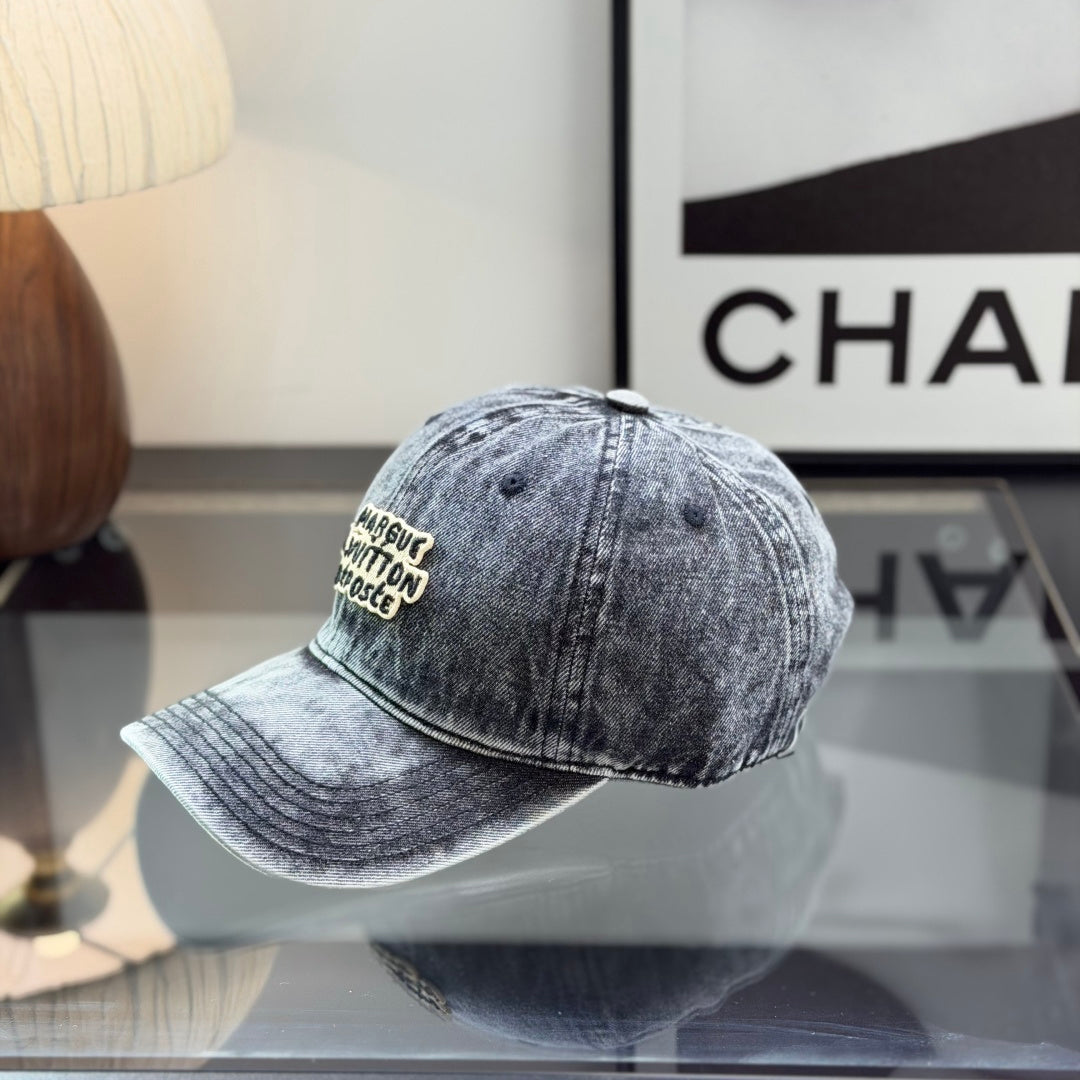 A grey distressed washed denim baseball cap with an embroidered patch on the front panel.